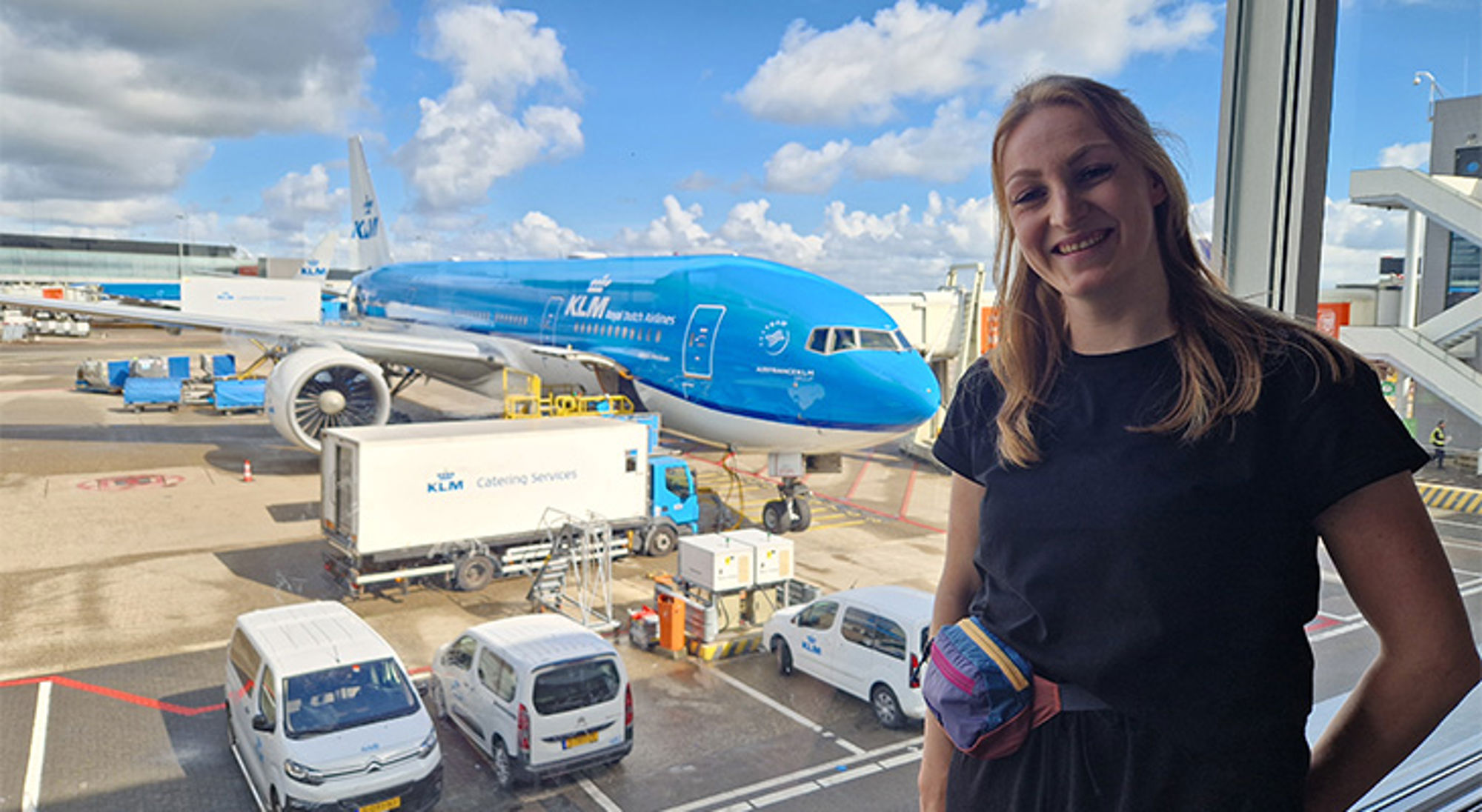 Celina op Schiphol Vrouw bij raam met KLM-vliegtuig op het platform van Schiphol Airport.