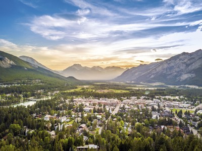 Uitzicht over Banff in de Canadese Rockies, met bergen en dennenbossen bij zonsondergang.
