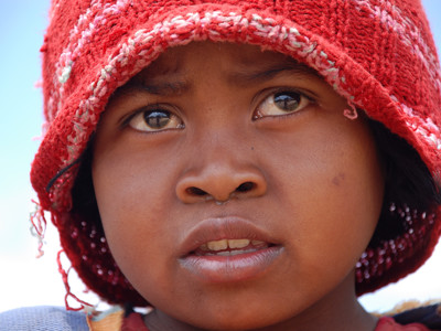 Portret van een meisje met rode gebreide muts tijdens de 19-daagse Route Madagascar.