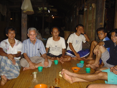 Mannen zitten op een rieten mat in een traditioneel longhouse op Maleisisch Borneo en drinken samen thee.