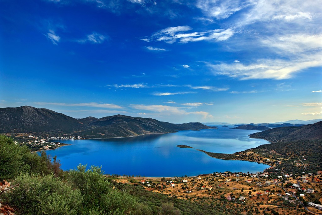 Uitzicht over een blauwe baai met bergen en dorpen op Evia, Griekenland.