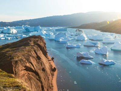 Uitzicht op een fjord met drijvende ijsbergen vanaf een rotsachtige kust in Groenland.