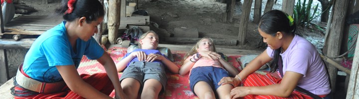 Kinderen krijgen een traditionele massage tijdens een reis, terwijl ze ontspannen op een mat liggen.