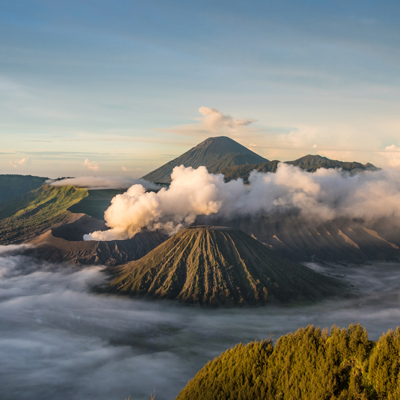 Zonsopkomst bij de Bromo-vulkaan op Java, met rookpluimen en wolken boven de krater.