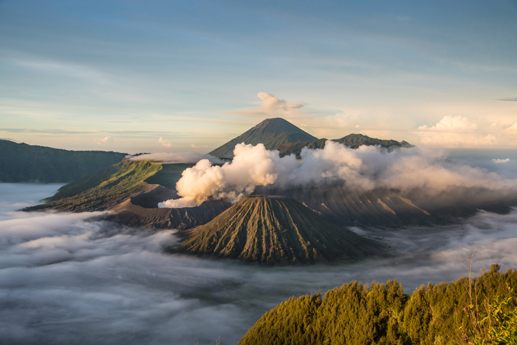 Zonsopkomst bij de Bromo-vulkaan op Java, met rookpluimen en wolken boven de krater.