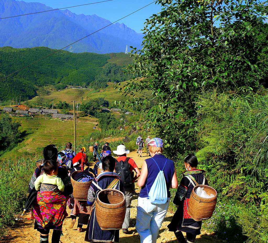Wandelaars tijdens groepsrondreis Vietnam op bergpad langs rijstterrassen en dorpen.