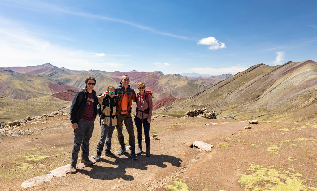 Jonge reizigers tijdens een groepsrondreis Peru, poseren bij de gekleurde bergen van Vinicunca.