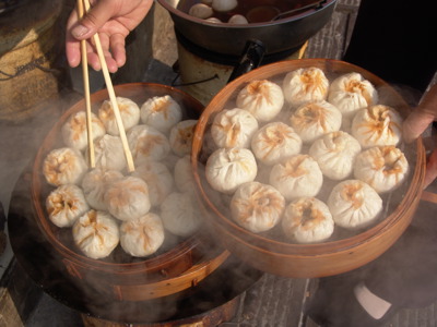 Gestoomde Chinese dumplings in bamboemandjes, gepakt met eetstokjes.