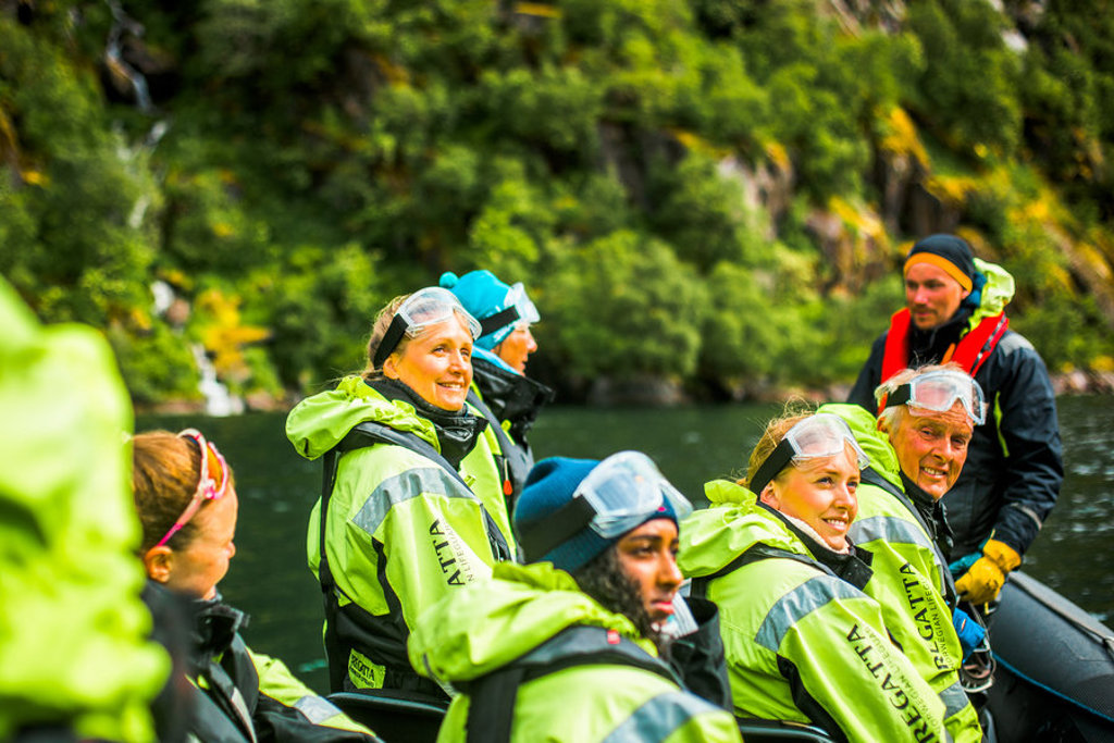 Groepsrondreis Noorwegen: reizigers in beschermende pakken tijdens een boottocht op een fjord.