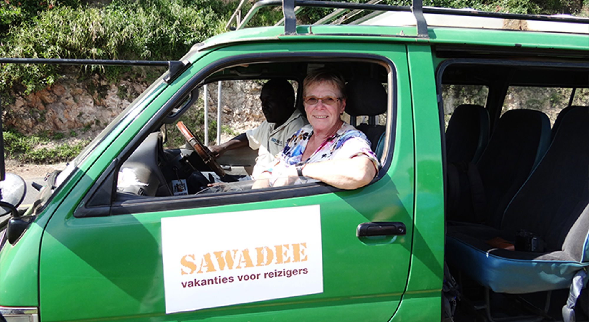 Reiziger in groene safariwagen met SAWADEE-logo tijdens rondreis.