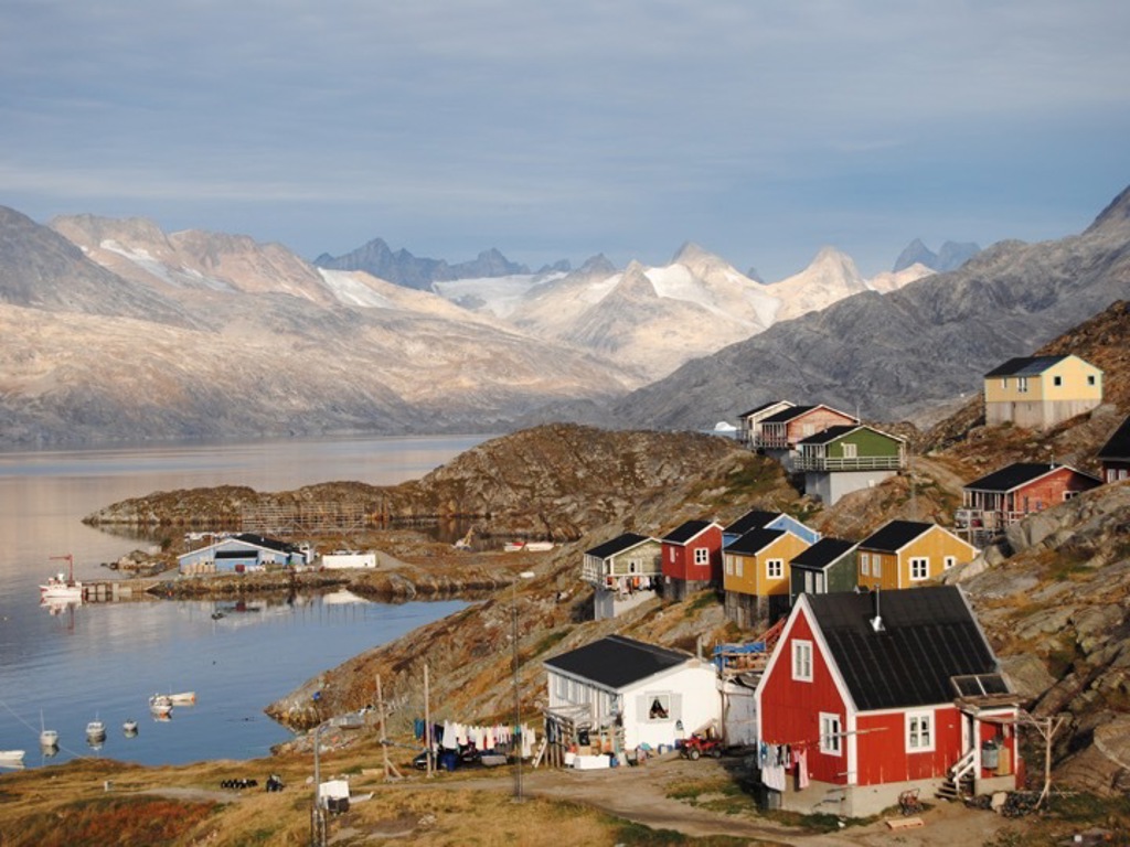 Kleurrijke huizen aan een fjord met bergen en gletsjers op de achtergrond tijdens groepsrondreis Groenland expeditie.