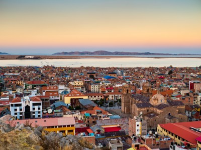 Panoramisch uitzicht op Puno aan het Titicacameer bij zonsondergang, met de kathedraal en kleurrijke daken.