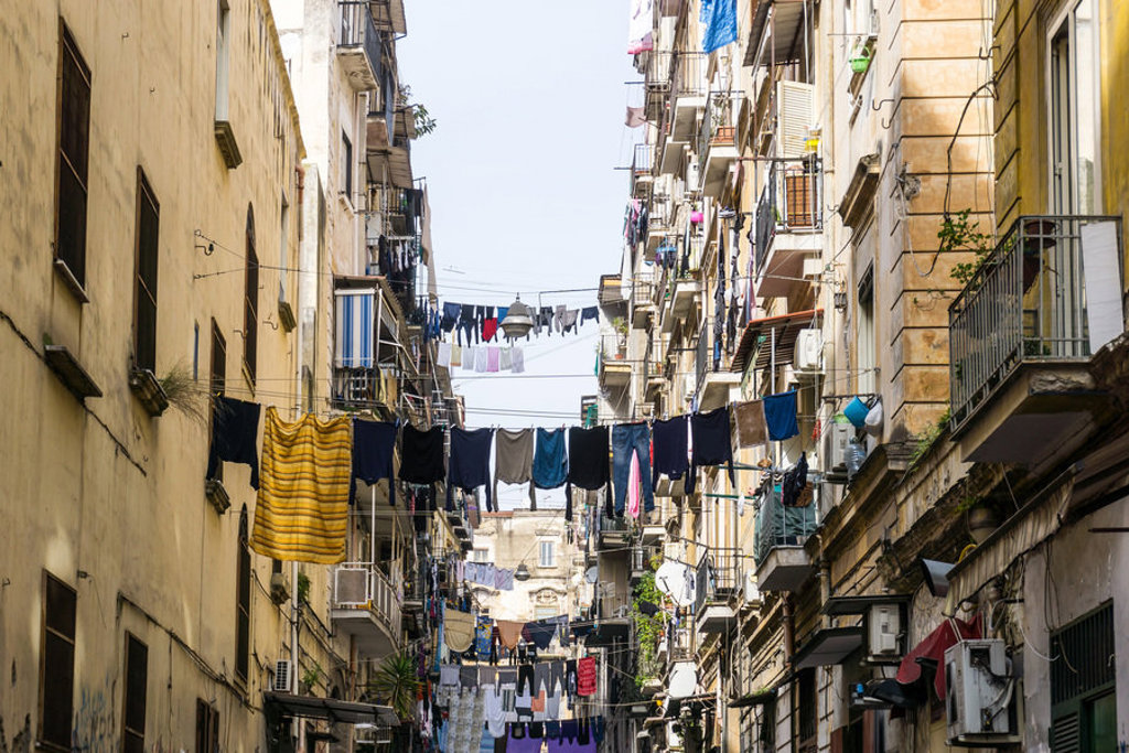 Smalle straat in Zuid-Italië met balkons en wasgoed dat tussen de gebouwen hangt.