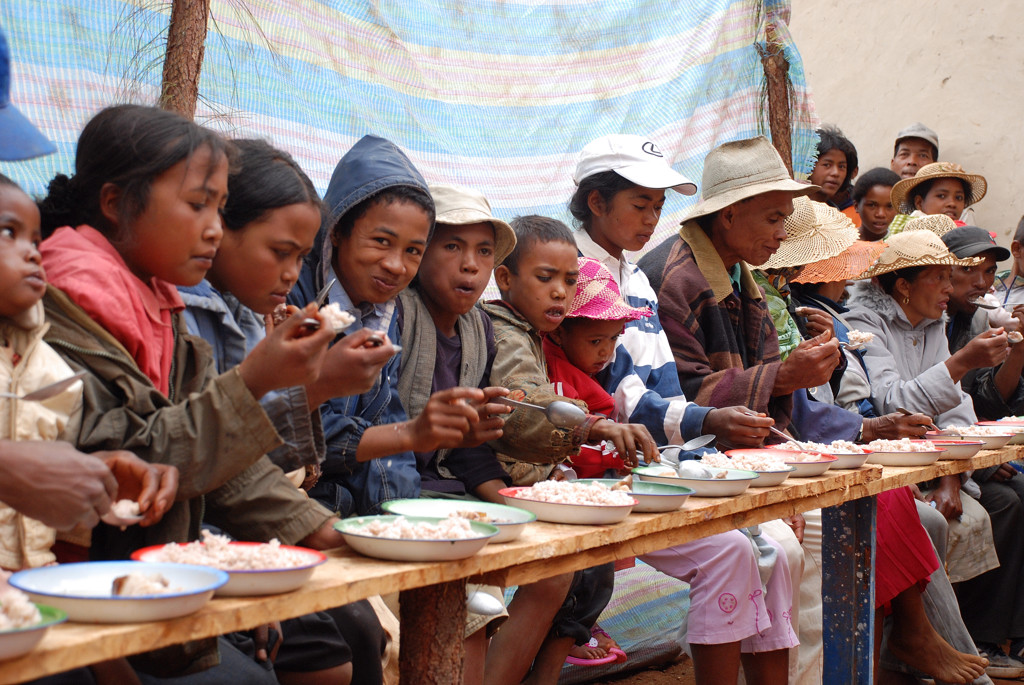 Lokale bewoners eten samen aan lange tafel tijdens een maaltijd in Madagascar.