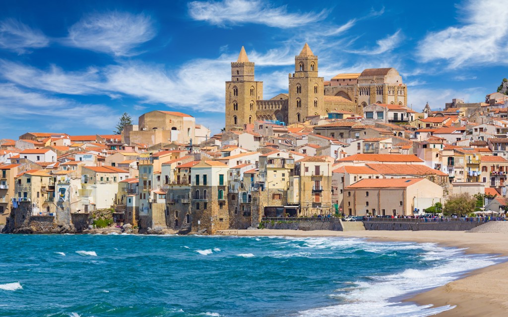 Kustplaats Cefalù op Sicilië met strand en de Normandische kathedraal op de heuvel.