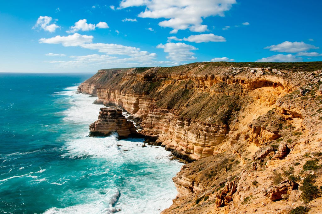 Rotsachtige kliffenkust aan de Indische Oceaan in West-Australië, met golven en blauwe lucht.