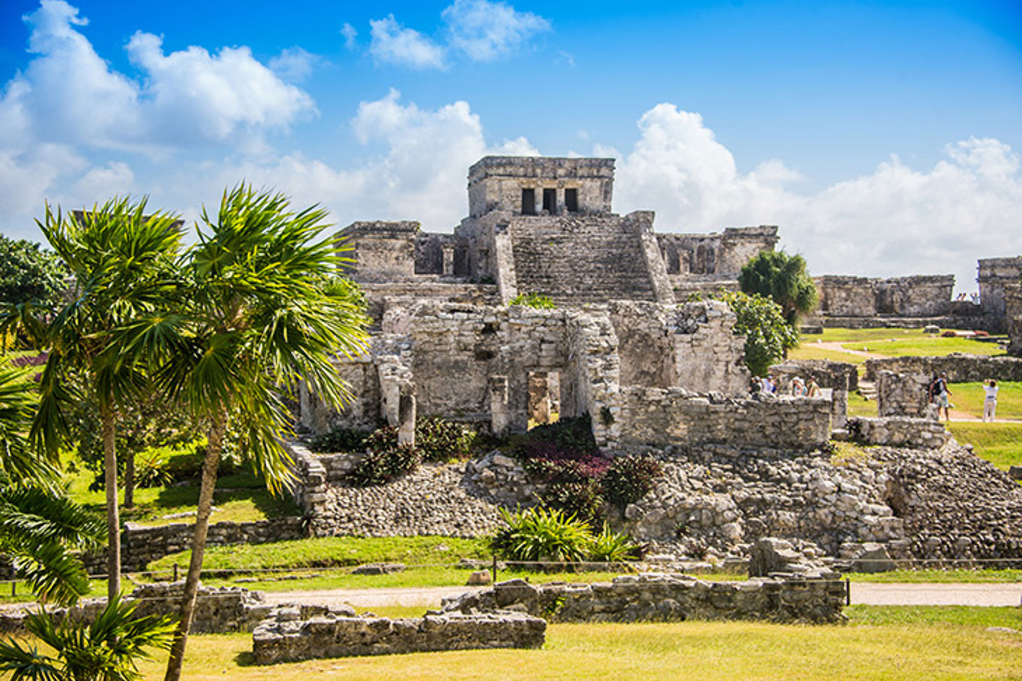 Tempelcomplex, Mexico Maya-ruïnes van Tulum met palmbomen onder een blauwe lucht.
