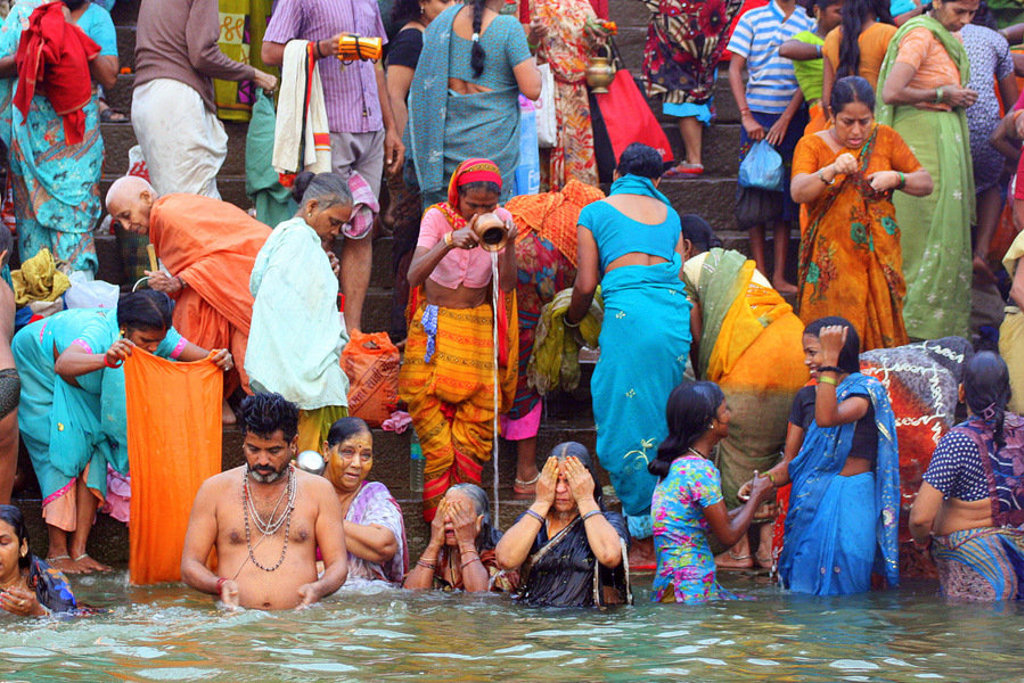 Kleurrijke drukte bij een heilige rivier in Noord-India, waar pelgrims baden en offers brengen.