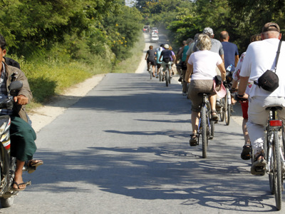 Fietstocht met groep reizigers over een landelijke weg in Myanmar tijdens de 25-daagse Route Birma.