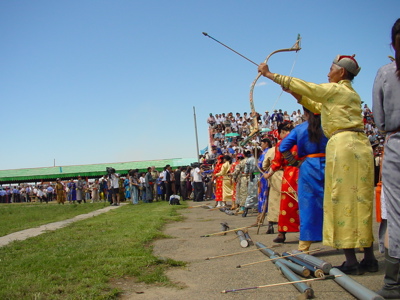 Boogschutter in traditionele kleding tijdens het Naadam Festival in Mongolië, met publiek op de tribune.