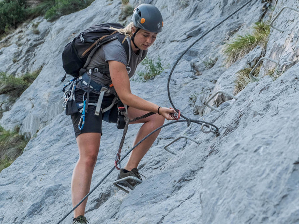 Vrouw op via ferrata met helm en klimgordel in de Pyreneeën bij Canigou, Frankrijk.