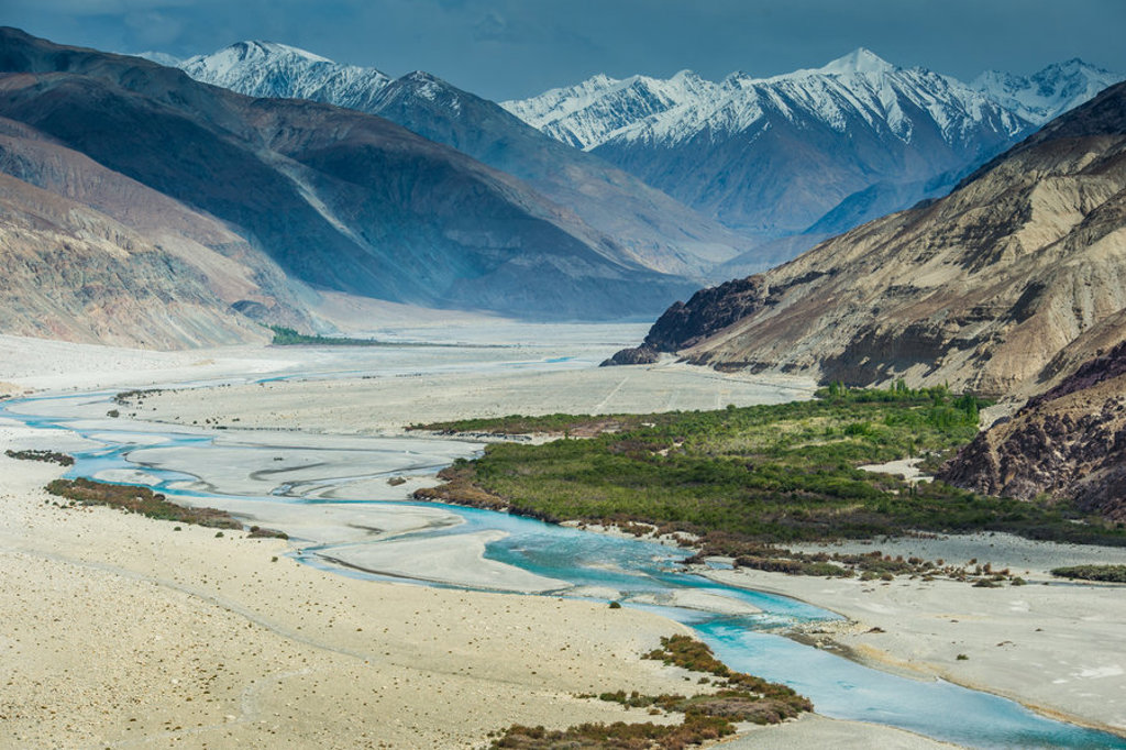 Rivierdal met kronkelende blauwe rivier en besneeuwde bergen in Ladakh, India.