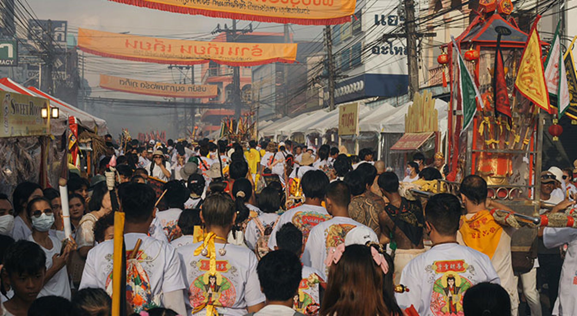 Vegetarisch festival in Phuket Drukke straatprocessie tijdens Chinees festival met vlaggen, banieren en menigte in de stad.