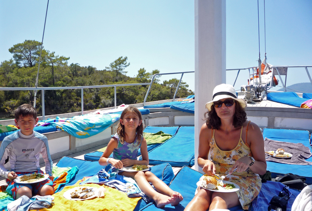 Gezin luncht op het dek van een boot langs de Turkse turquoise kust tijdens een familiereis Turkije.