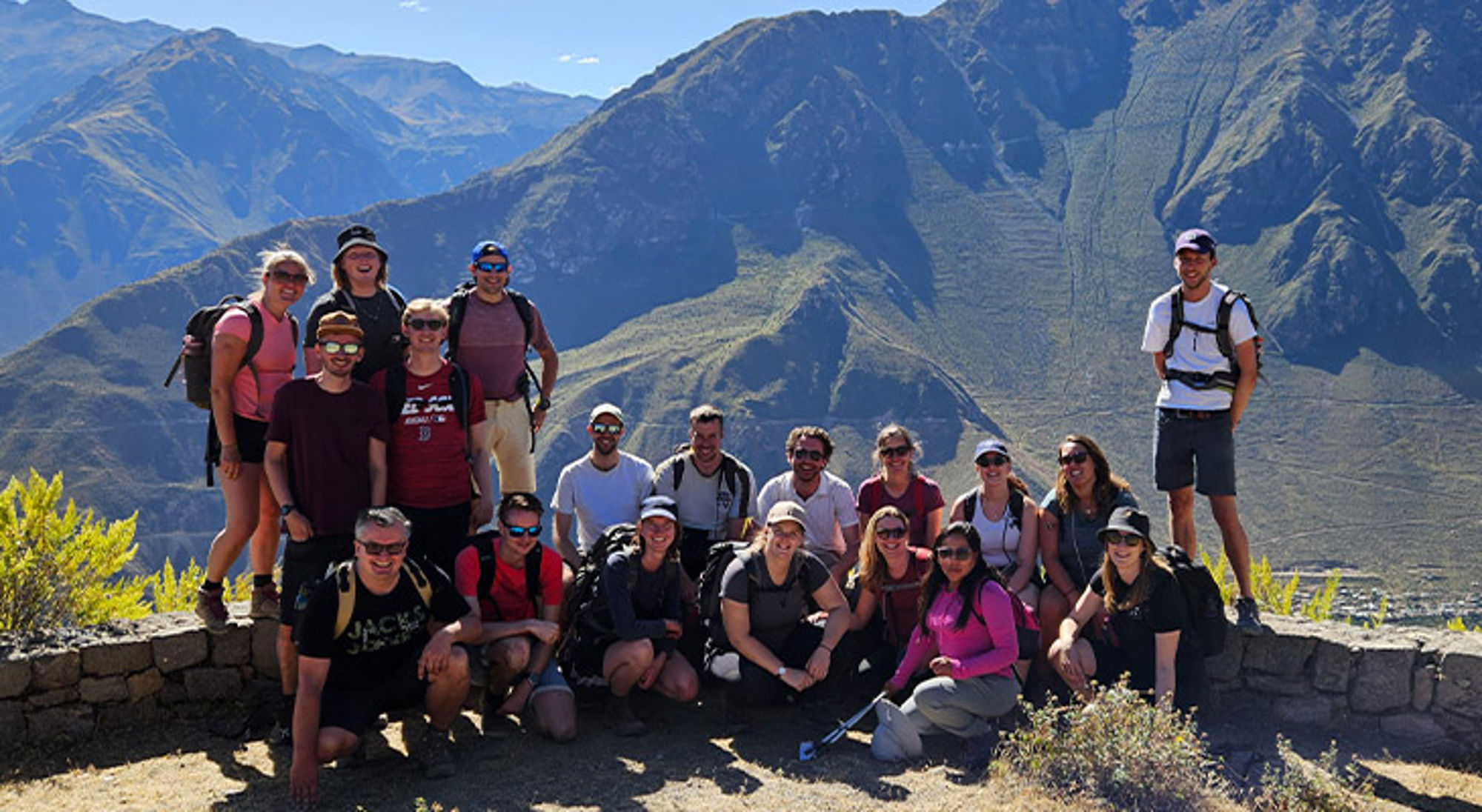 22-35ers reis Peru Groep wandelaars poseert bij een uitkijkpunt met berglandschap op de achtergrond.