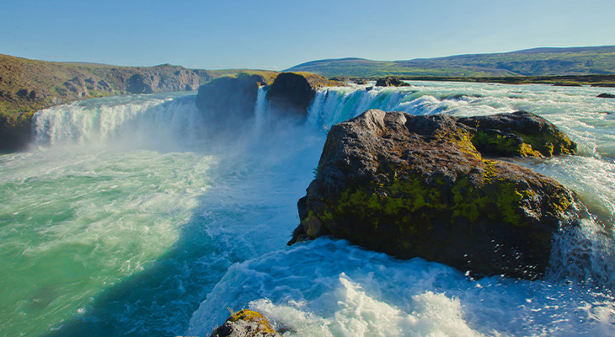 Niagara Falls Krachtige waterval met turquoise water en rotsen in een groen heuvellandschap.