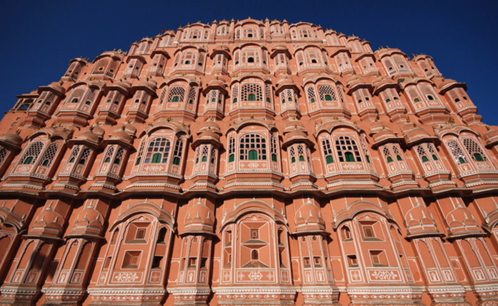 Hawa Mahal (Paleis der Winden) in Jaipur, Rajasthan, met roze gevel en vele ramen tegen een blauwe lucht.