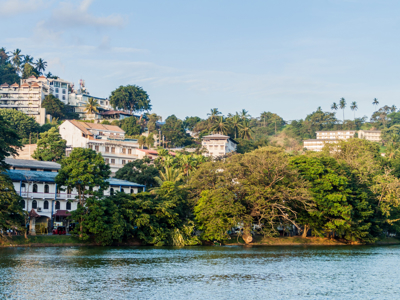 Uitzicht op Kandy vanaf het meer, met hotels en palmbomen in het groen langs de oever in Sri Lanka.