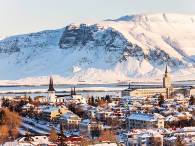 Sneeuwbedekte stad Reykjavik met Hallgrímskirkja en bergen op de achtergrond tijdens Route IJsland Winter.