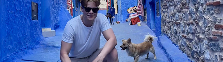 Olivier in een blauw steegje in Chefchaouen, Marokko, met een hond.