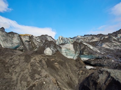 Gletsjerlandschap met ijsformaties en zwarte vulkanische as tijdens de 7-daagse wandelvakantie in IJsland.
