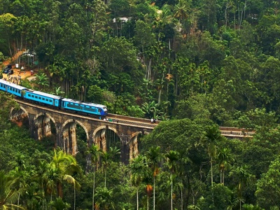 Blauwe trein over de Nine Arch Bridge bij Ella, Sri Lanka, omringd door groene heuvels en jungle.