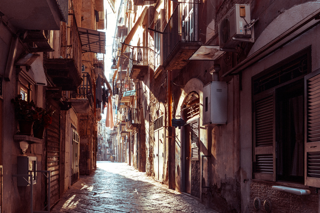 Smalle steeg met balkonnetjes en zonlicht in een dorp aan de Amalfikust, Italië.