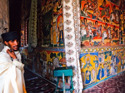Priester in Ethiopische kerk met kleurrijke muurschilderingen, Route Ethiopië 29 dagen.