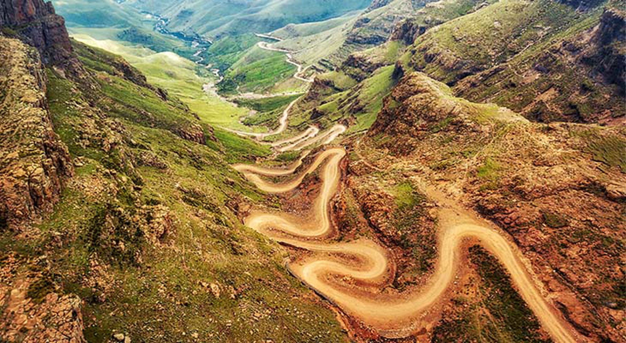 Kronkelende weg van Sani Pass Groene savanne met hoge bomen en struiken in Zuid-Afrika.