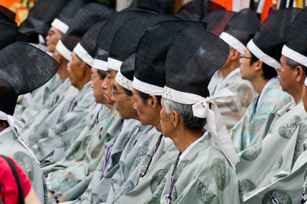 Japanse festivaldeelnemers in traditionele kledij met zwarte hoeden, tijdens een groepsrondreis Japan hoogtepunten.