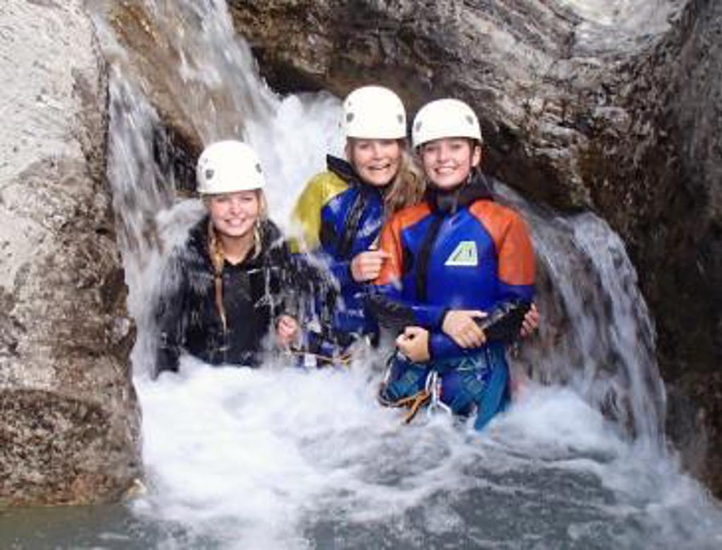 Gezin met helmen en wetsuits in een bergkloof met waterval tijdens canyoning in Mercantour-Vésubie, Frankrijk.