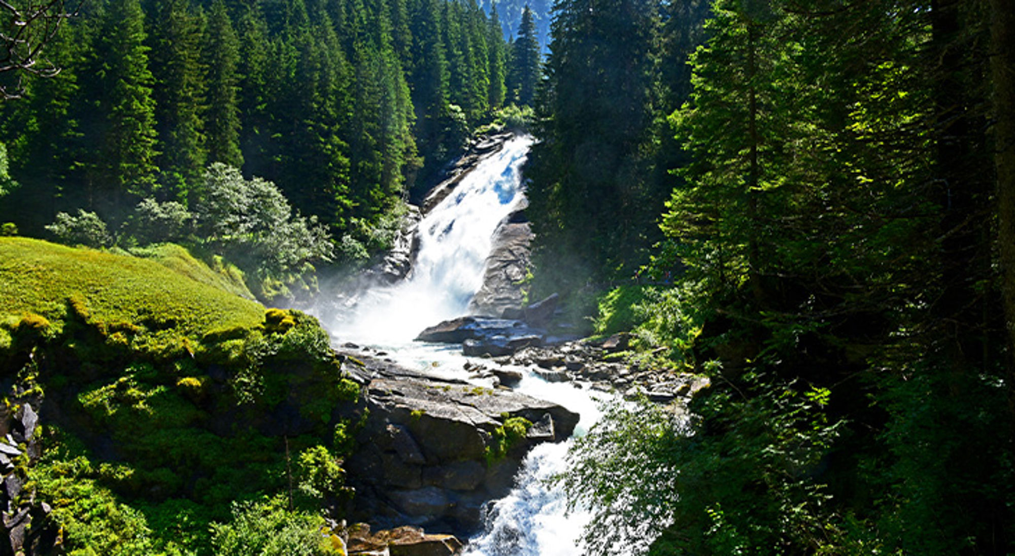 Krimmler Waterval Noorwegen Waterval in een groen bergbos met rotsen en stromende rivier.