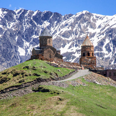 Gergeti Drievuldigheidskerk bij Kazbegi in Georgië, met besneeuwde Kaukasusbergen op de achtergrond.