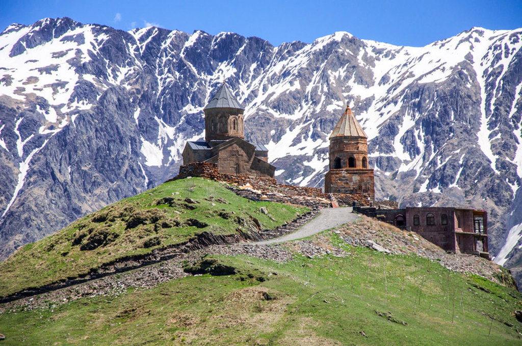 Gergeti Drievuldigheidskerk bij Kazbegi in Georgië, met besneeuwde Kaukasusbergen op de achtergrond.