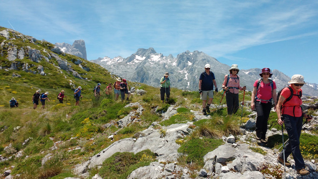 Wandelaars op bergpad in de Picos de Europa, Spanje, met ruige bergtoppen op de achtergrond.