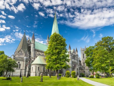 Nidarosdom in Trondheim met groene torenspits en park onder blauwe lucht, Route Noorwegen.