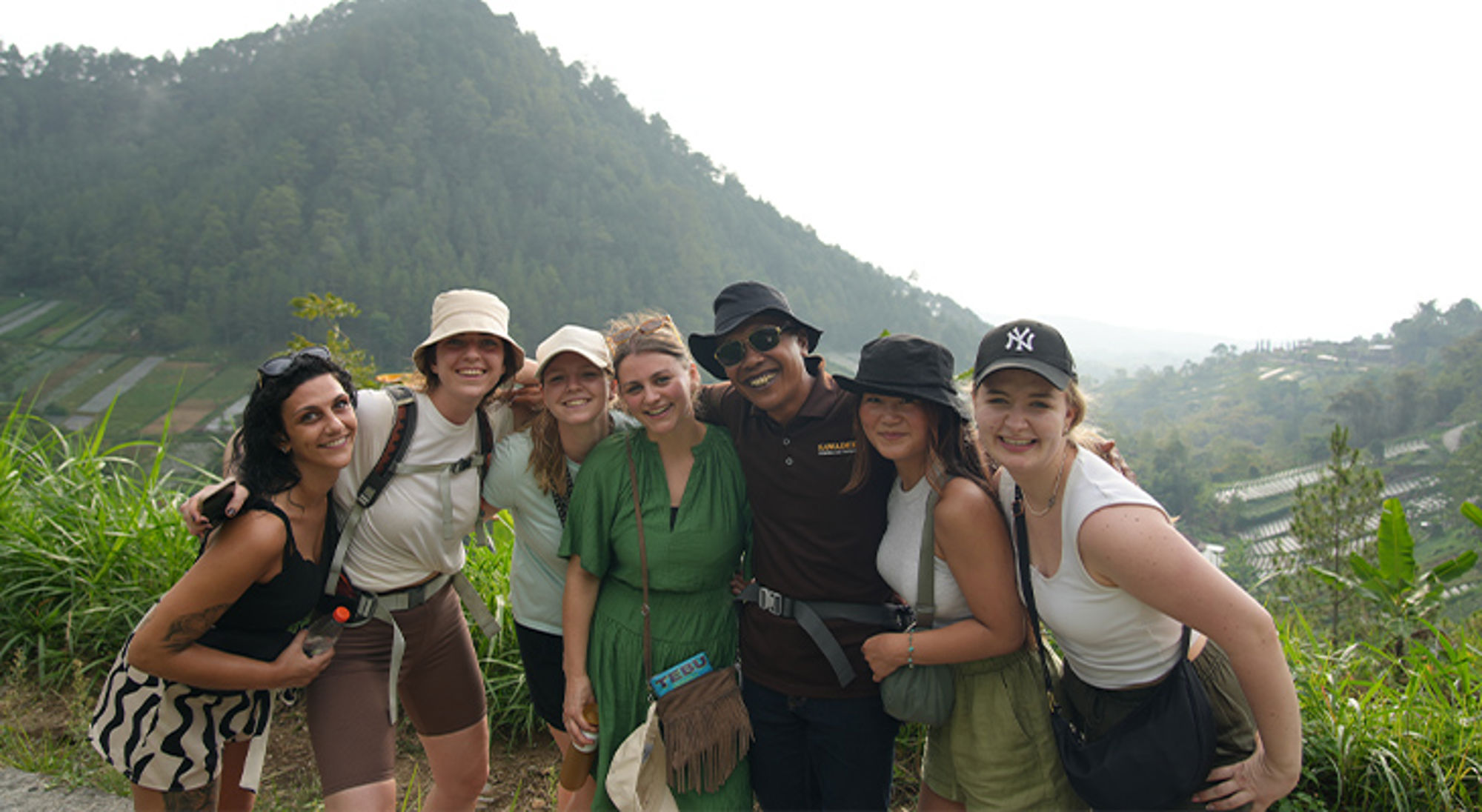 Tawangmangu Java Groep reizigers poseert tijdens een hike met groene berghellingen en terrassenvelden op de achtergrond.