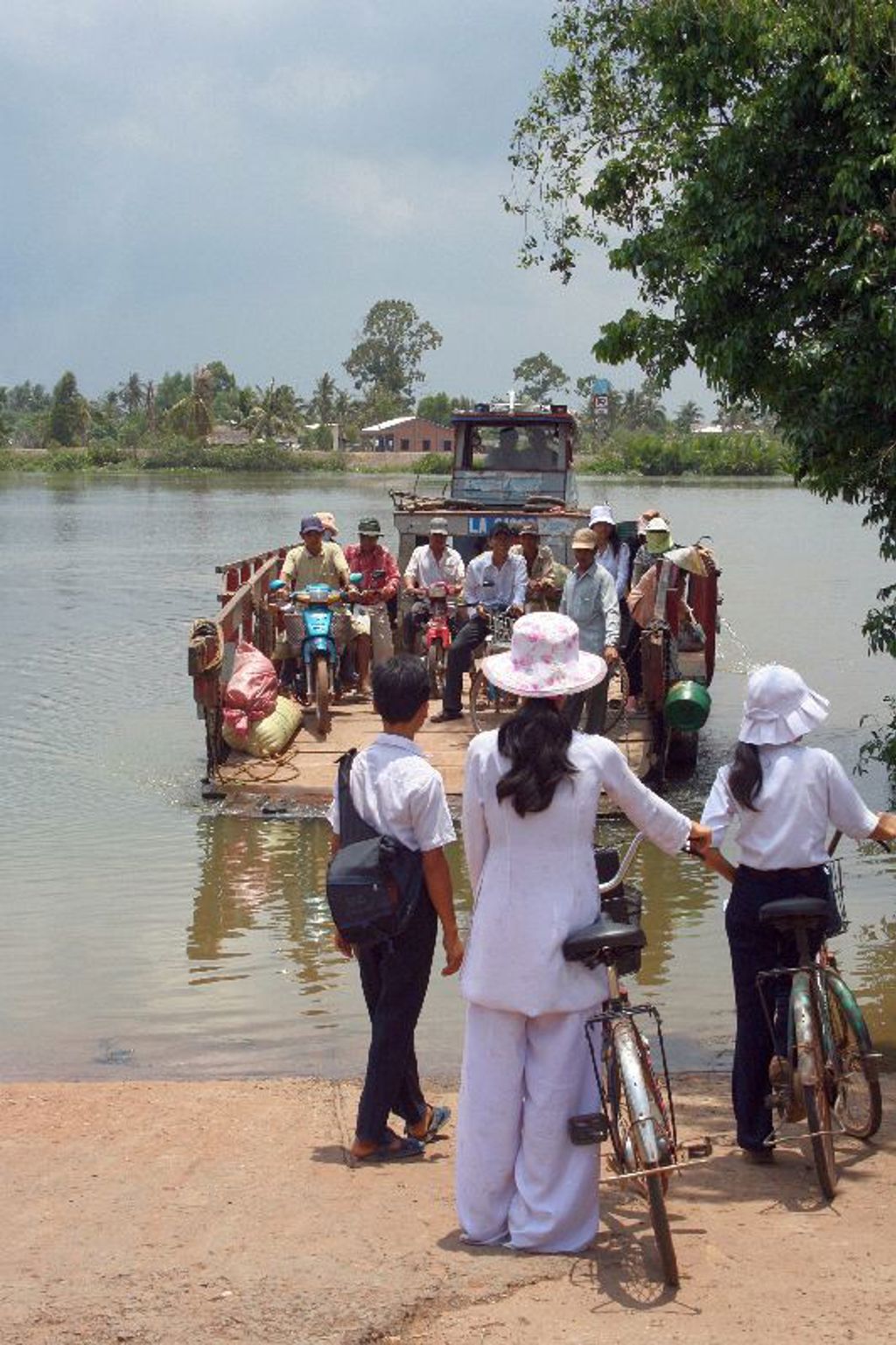 Reizigers met fietsen stappen op een veerboot over de Mekongdelta tijdens een groepsrondreis Vietnam.