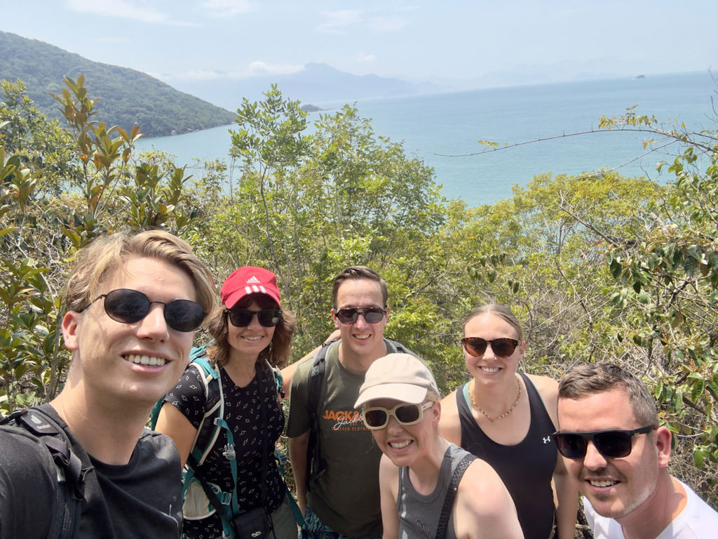 22-35ers groepsreis Brazilië: vriendengroep maakt selfie tijdens hike met uitzicht op zee en groene heuvels.