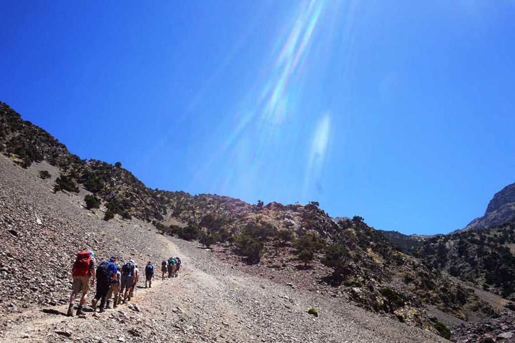 Wandelaars met rugzakken op bergpad tijdens beklimming van Mount Toubkal in Marokko.